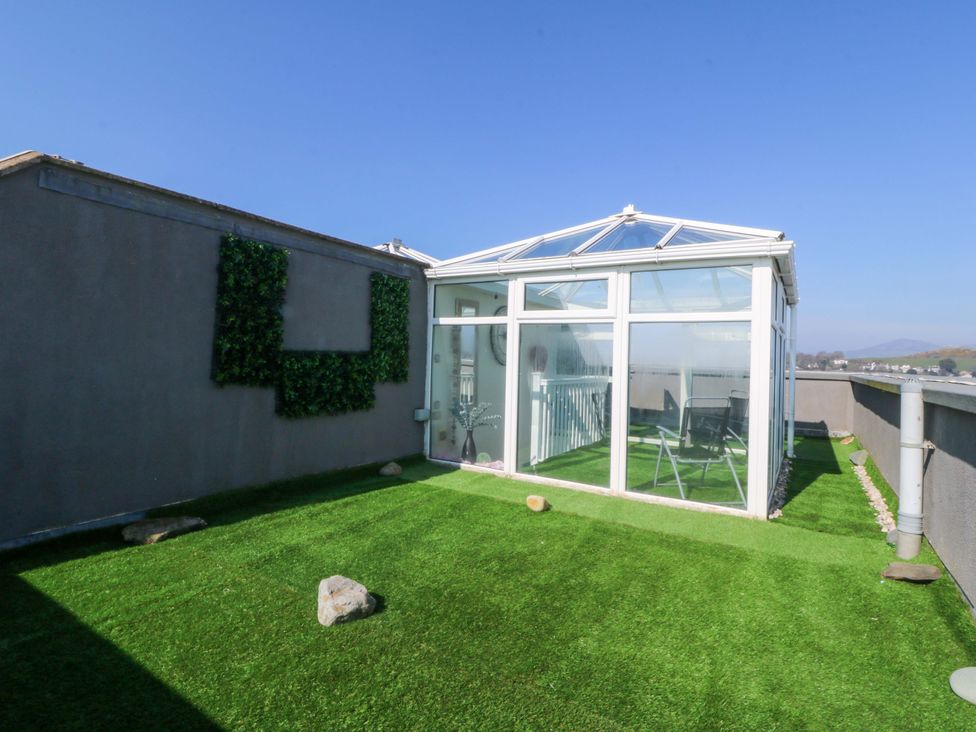 A conservatory with artificial grass and glass panels at Snowdonia View in Pwllheli