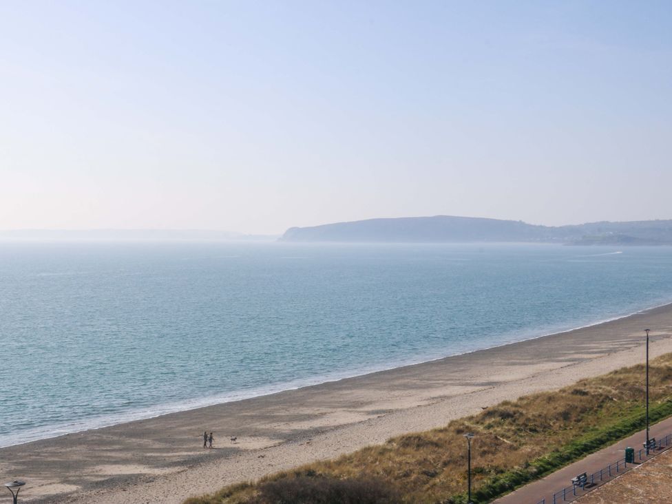 A beach with people walking and a dog at Snowdonia View in Pwllheli