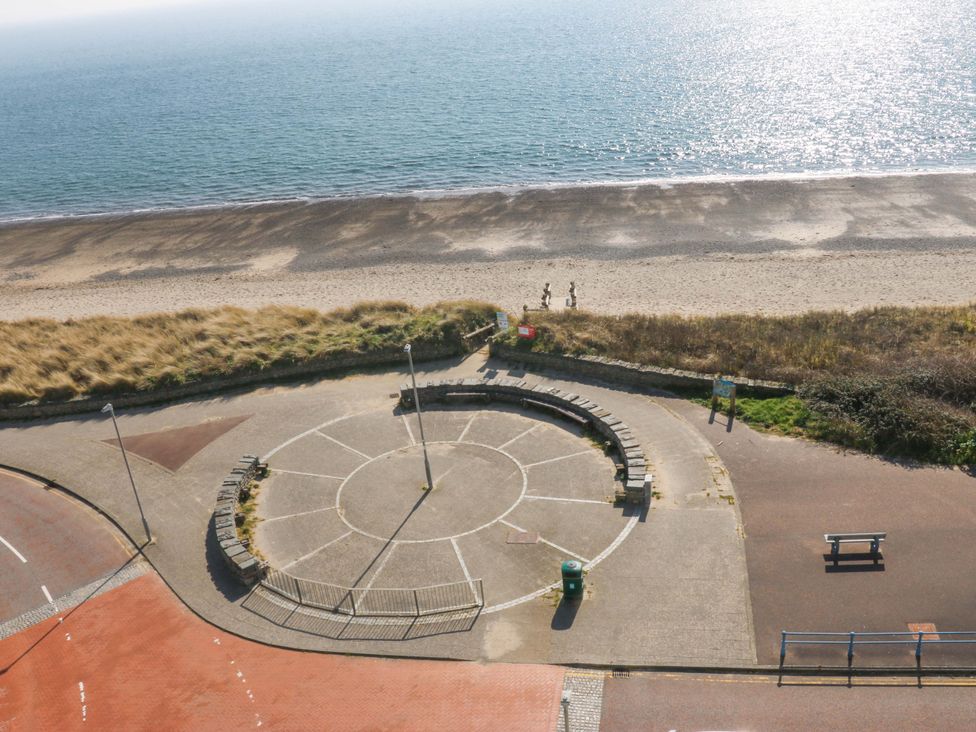 A beach with a circular seating area leading to the sea at Snowdonia View in Pwllheli