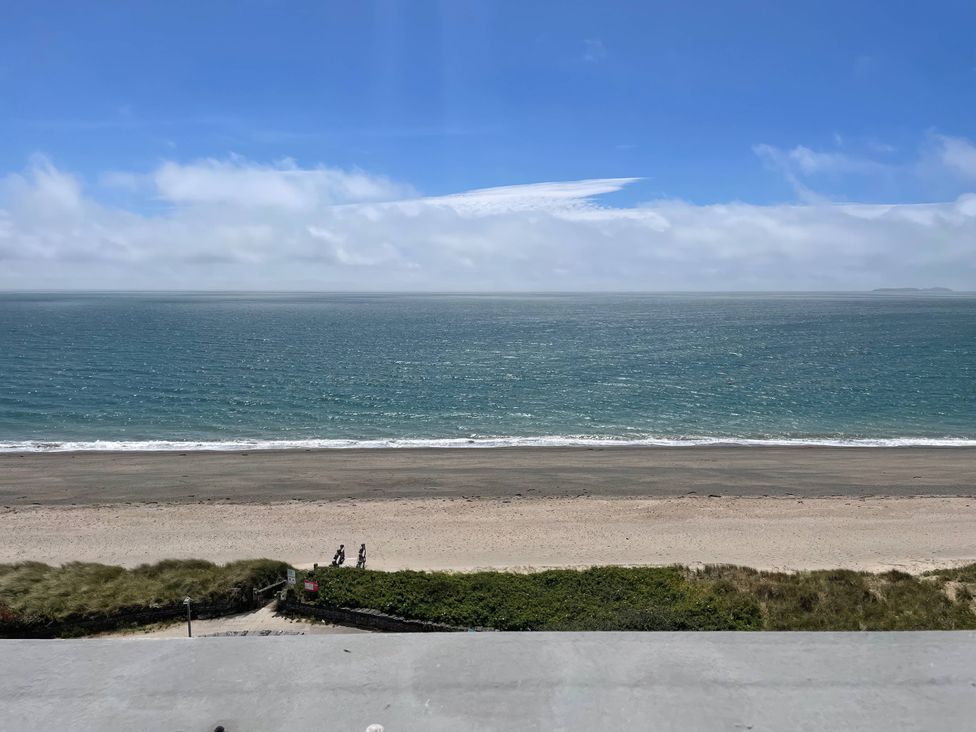 A view of the ocean and beach with people walking at Snowdonia View in Pwllheli