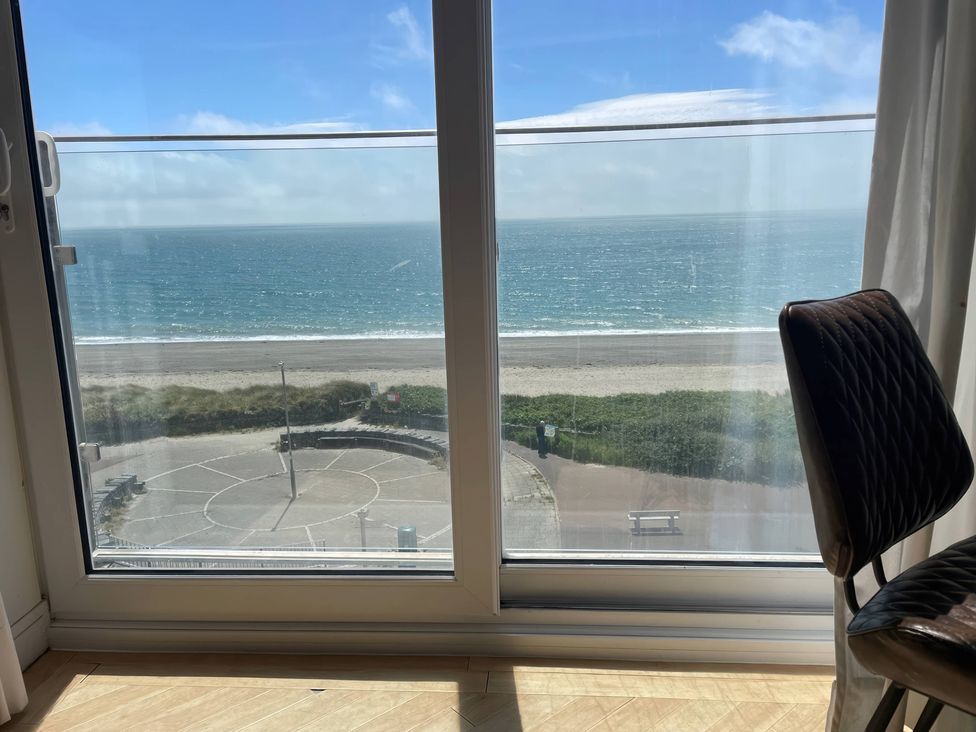 A view of the sea from a window with a chair at Snowdonia View in Pwllheli