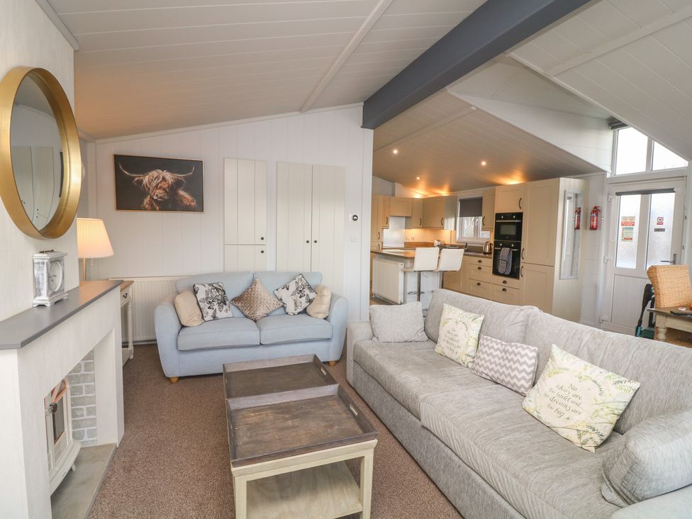 A living room with sofas and a kitchen area at Fairways 22 in Lincoln