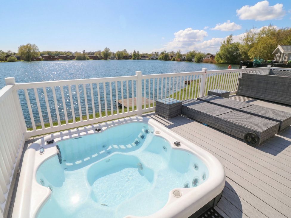 A hot tub on a deck with a view of a lake at Fairways 22 in Tattershall