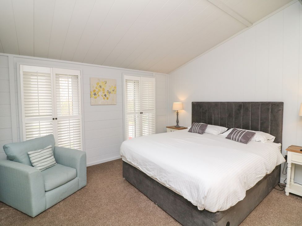 A bedroom with a bed and armchair at Fairways 22 in Tattershall