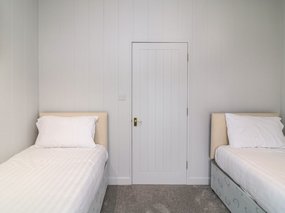 A bedroom with two single beds and a door at Fairways 22 in Tattershall