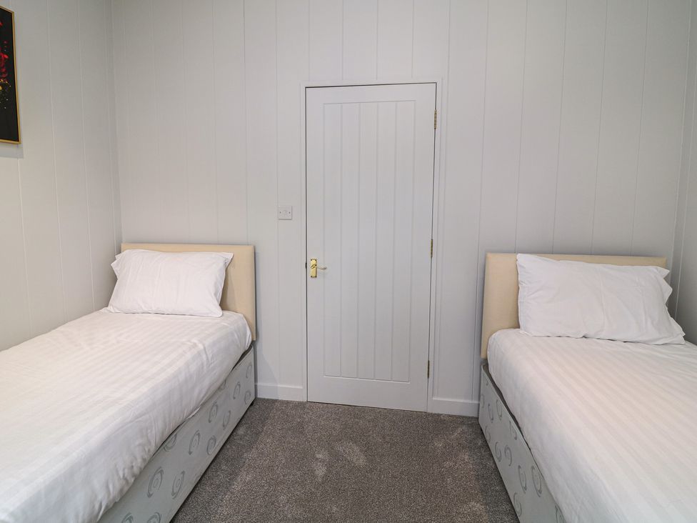 A bedroom with two single beds and a door at Fairways 22 in Tattershall