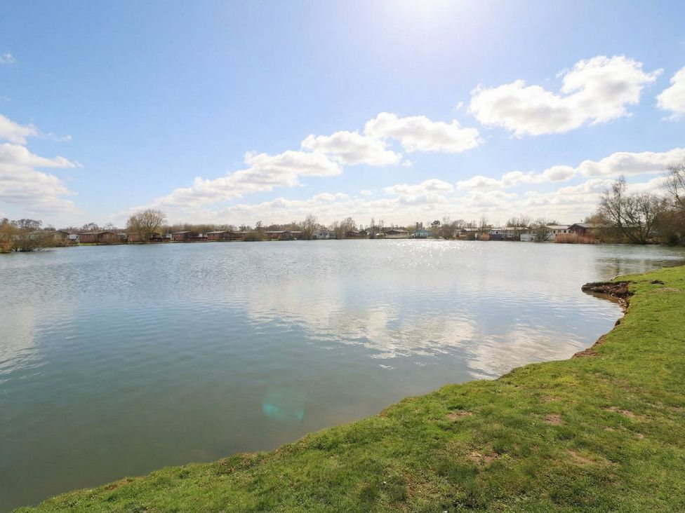 A lake with grass and trees at Fairways 22 Tattershall