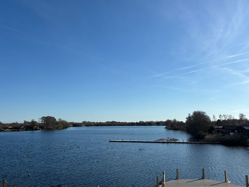 A view of a lake with a dock and houses at Indulgence Fishing Lodge with Private Hot Tub, Tattershall