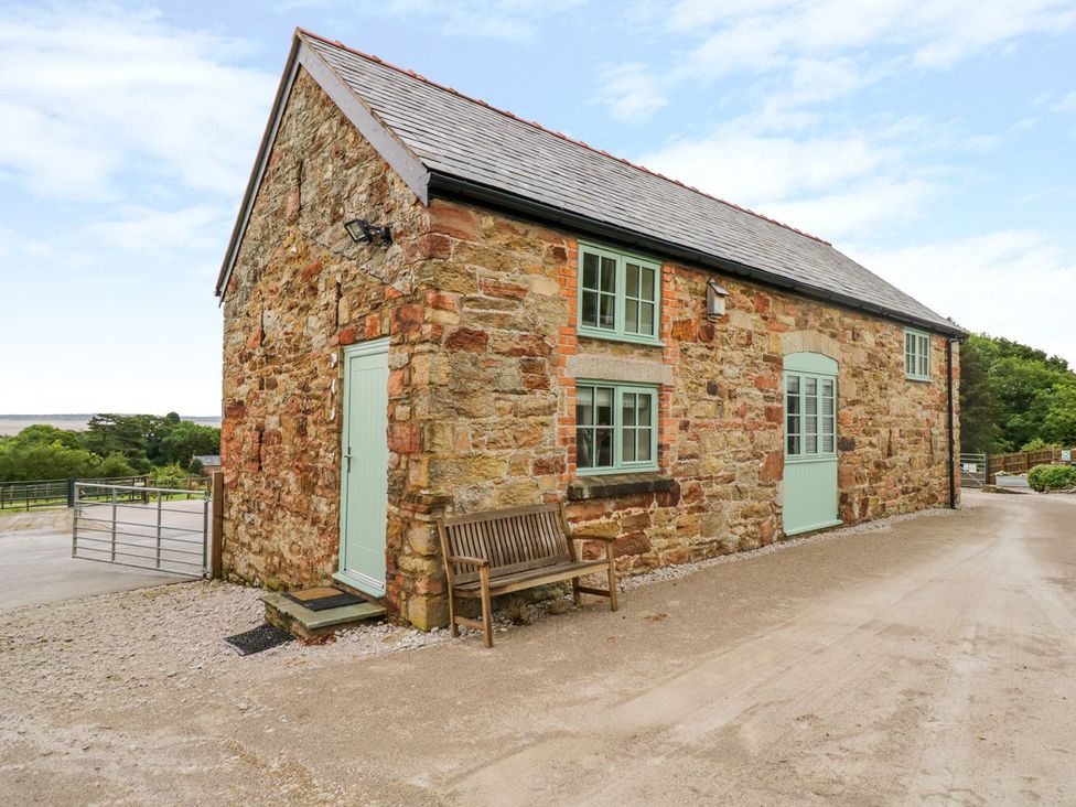 A rustic stone cottage with blue windows and door at Plas Tirion Cottage in Holywell