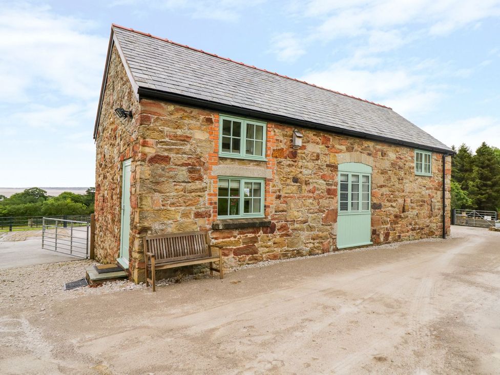 An exterior view of a stone building with green door at Plas Tirion Cottage Holywell
