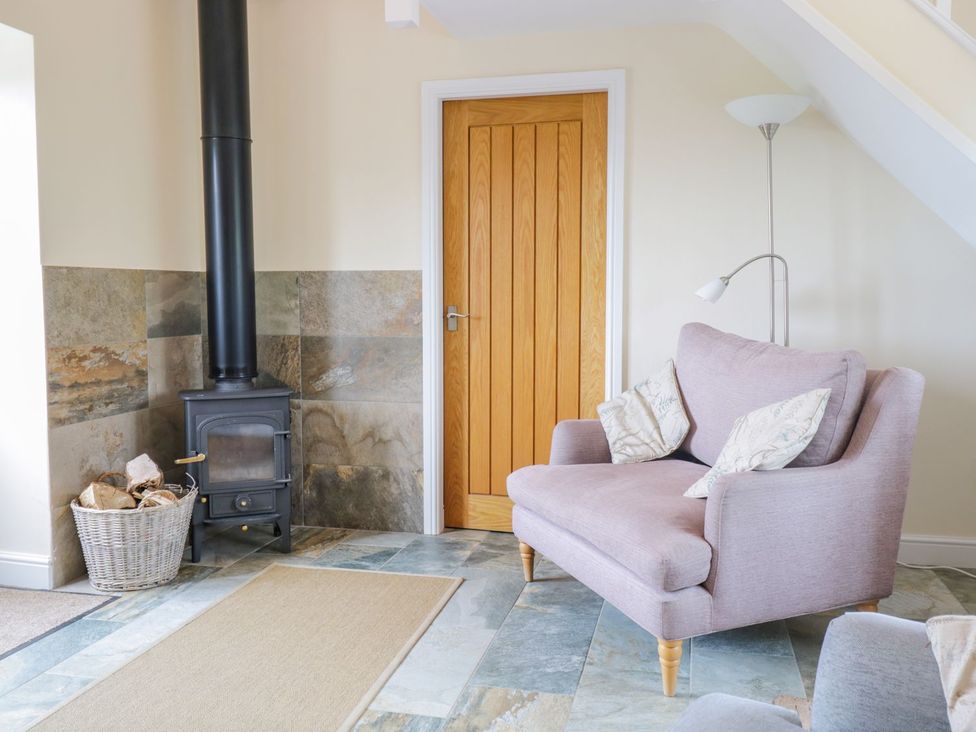 A living room with a stove and sofa at Plas Tirion Cottage Holywell