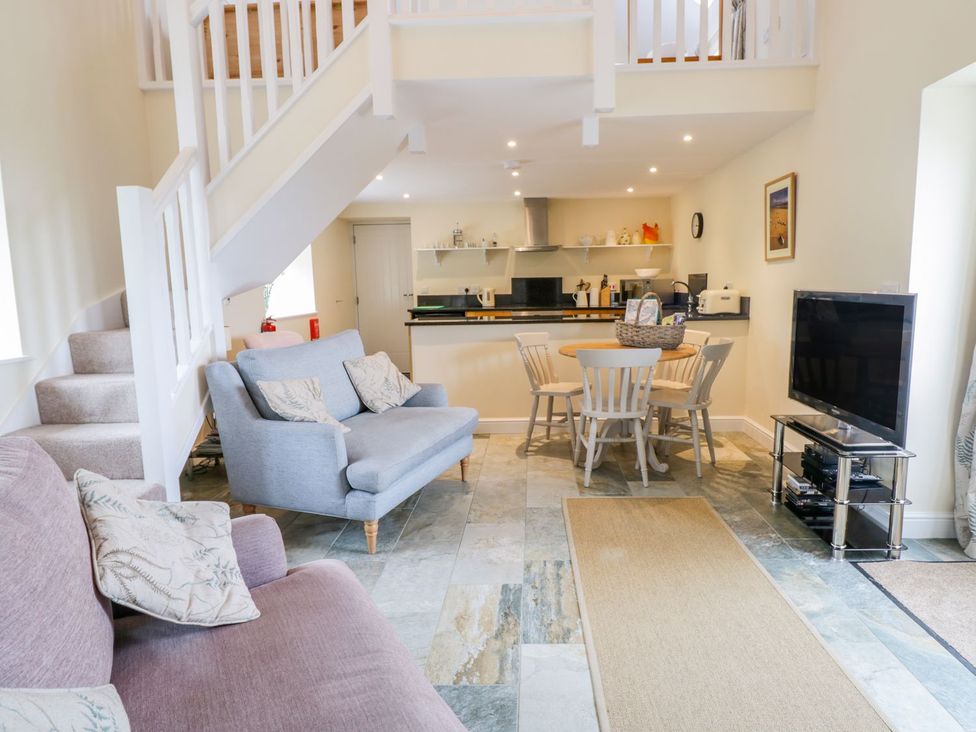 A living room with a dining area and kitchen unit at Plas Tirion Cottage in Holywell
