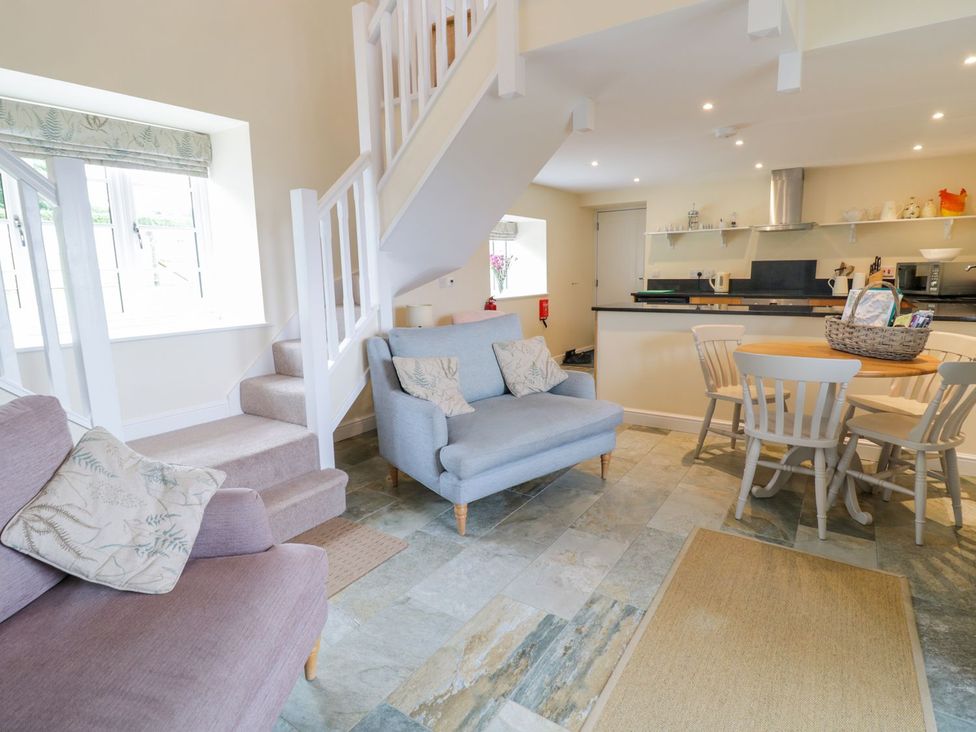 A living room with a sofa, armchair, and dining table at Plas Tirion Cottage in Holywell