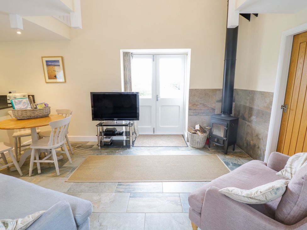 A living room with a television and dining area at Plas Tirion Cottage in Holywell