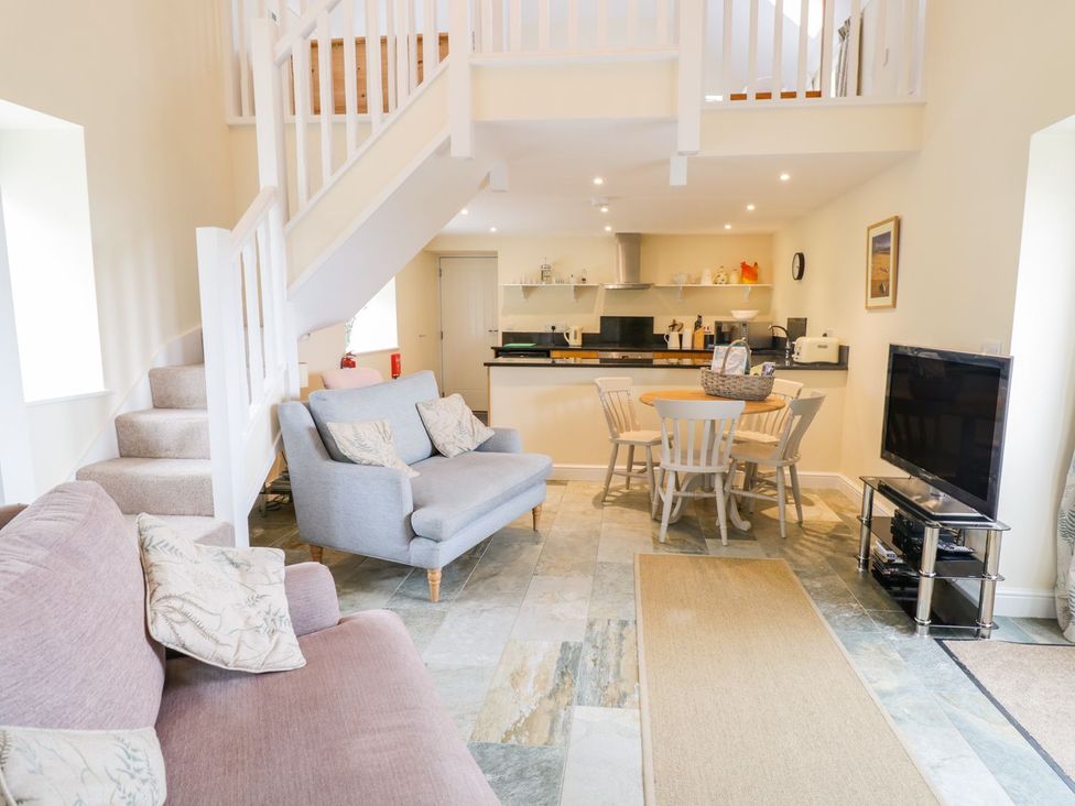A living room with a sofa and dining area at Plas Tirion Cottage Holywell