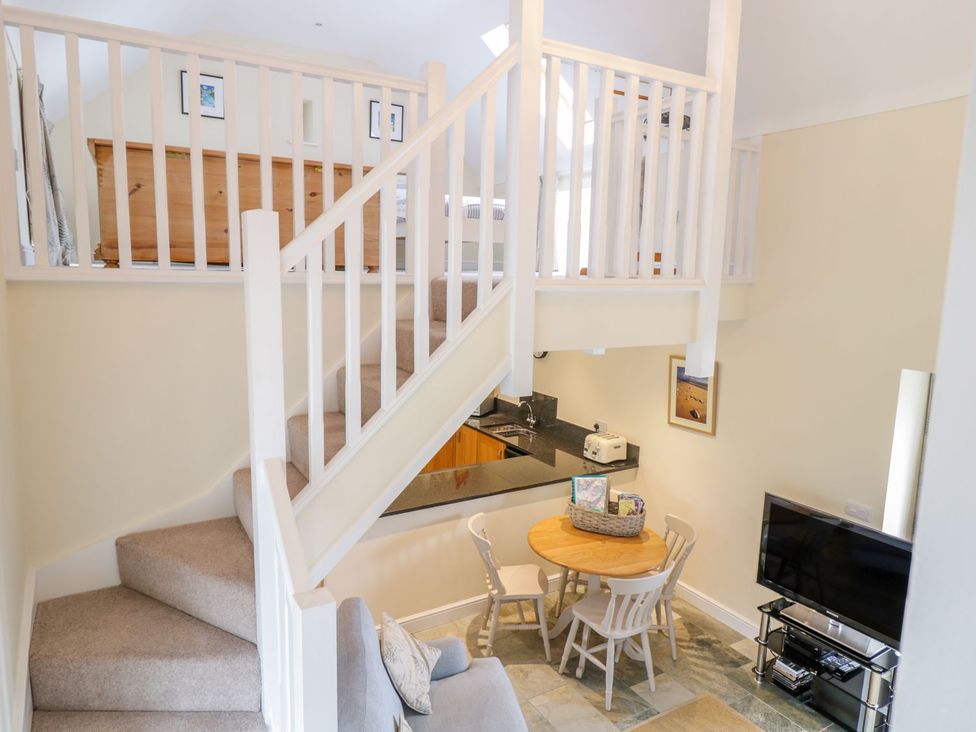 A living room with a staircase and kitchen area at Plas Tirion Cottage Holywell
