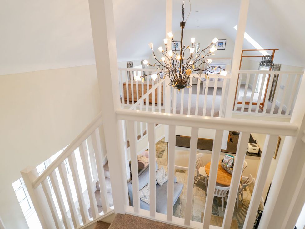 A living room with a staircase and chandelier at Plas Tirion Cottage Holywell