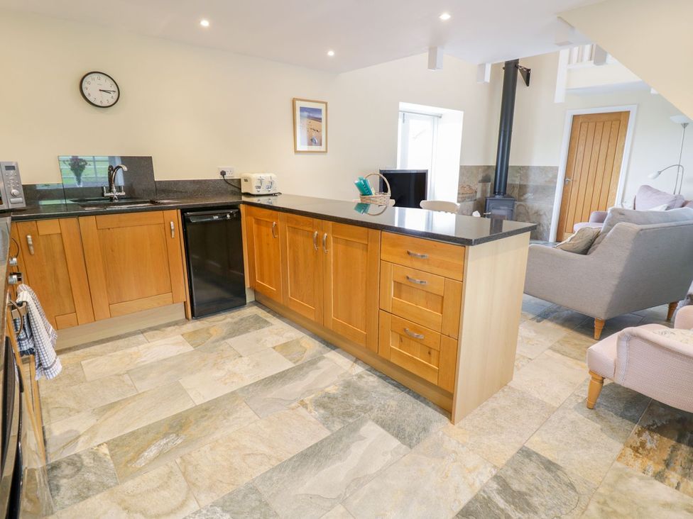 A kitchen with wooden cabinets and a sink at Plas Tirion Cottage Holywell