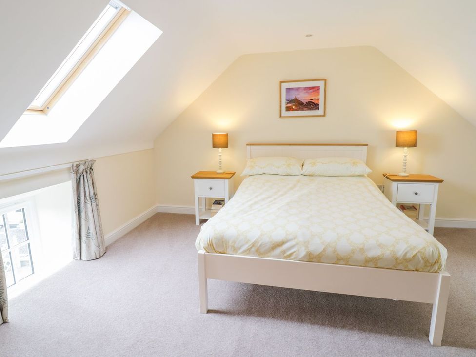 A bedroom featuring a bed with bedside tables and lamps at Plas Tirion Cottage in Holywell