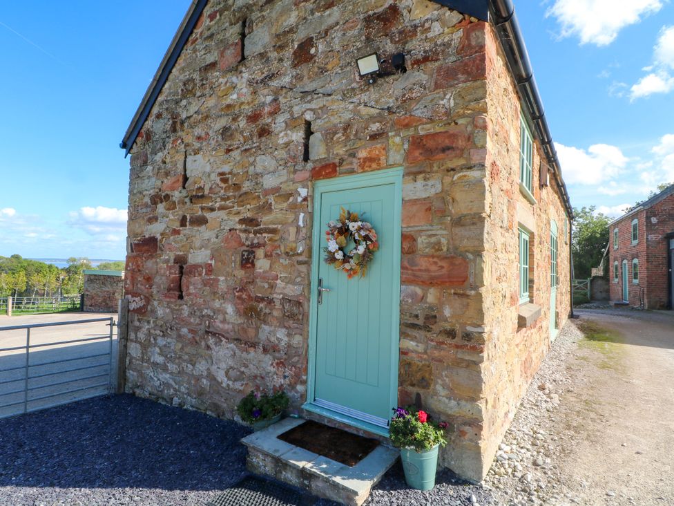 An entrance with a stone wall and a green door at Plas Tirion Cottage Mostyn near Holywell