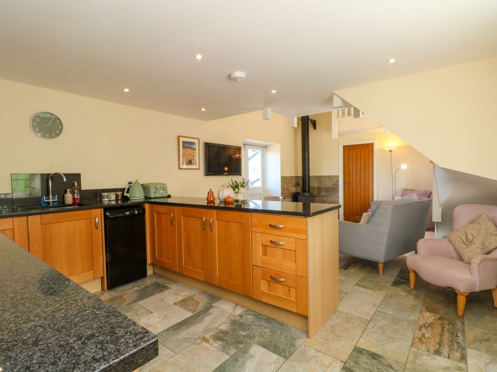 A kitchen with wooden cabinets and appliances at Plas Tirion Cottage Mostyn near Holywell