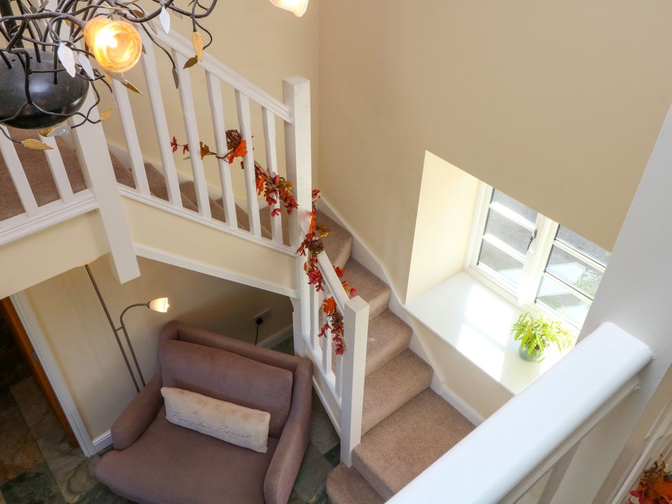 A staircase with a chandelier and a sofa at Plas Tirion Cottage Mostyn near Holywell
