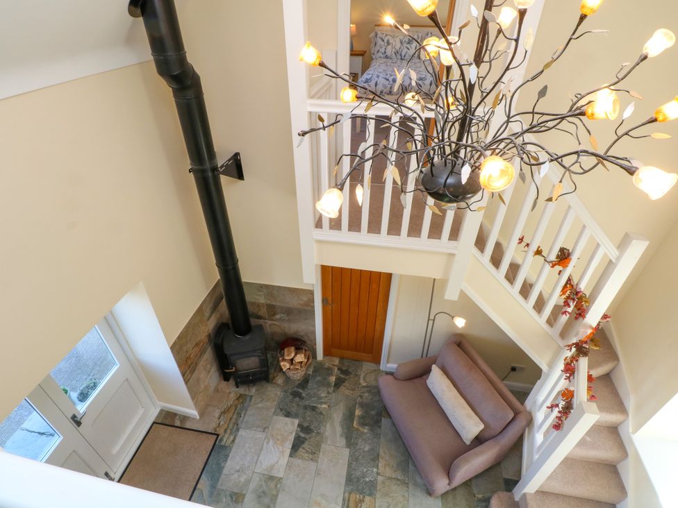 A hallway with a staircase and a fireplace at Plas Tirion Cottage Mostyn near Holywell