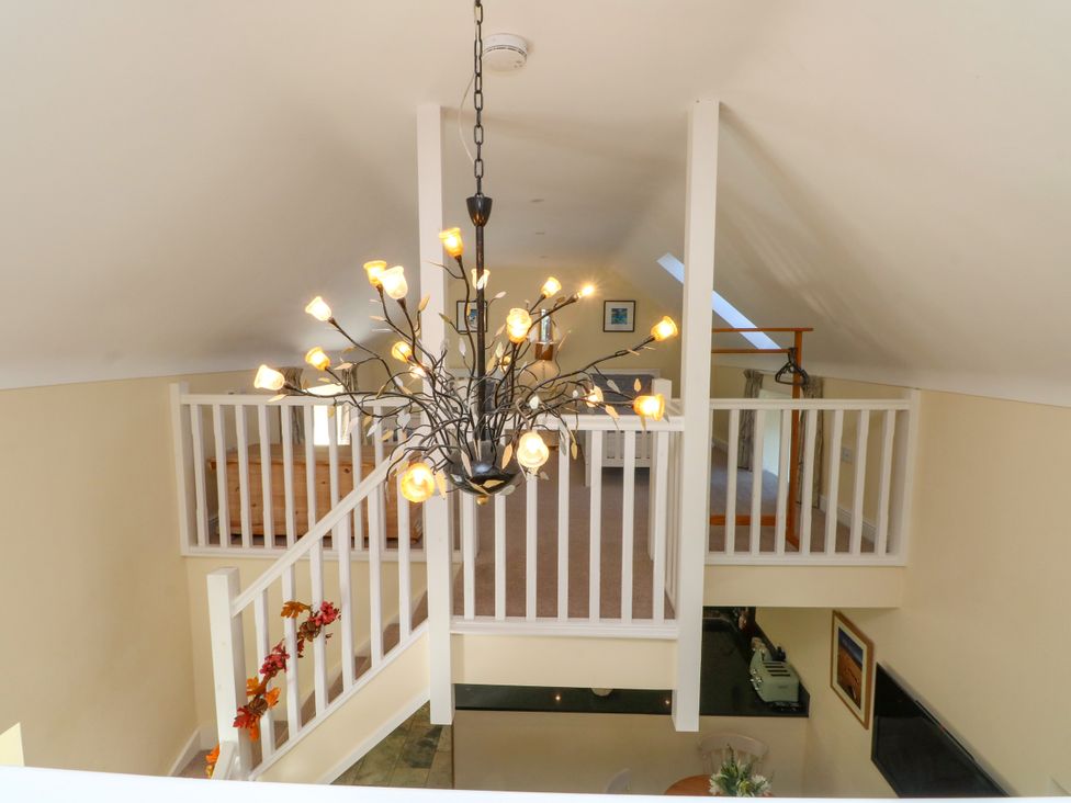 A living room with a chandelier and staircase at Plas Tirion Cottage Mostyn near Holywell