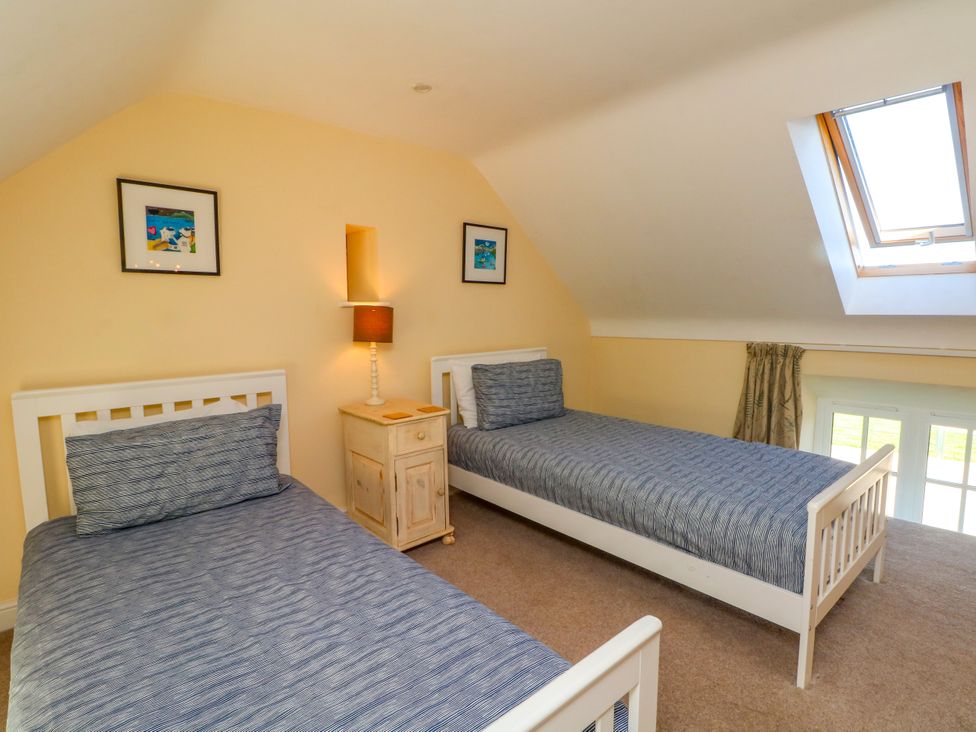 A bedroom with two beds and a bedside table at Plas Tirion Cottage Mostyn near Holywell