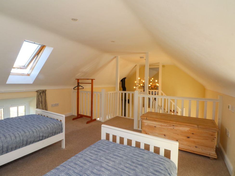 A loft with two beds and a clothing rack at Plas Tirion Cottage Mostyn near Holywell
