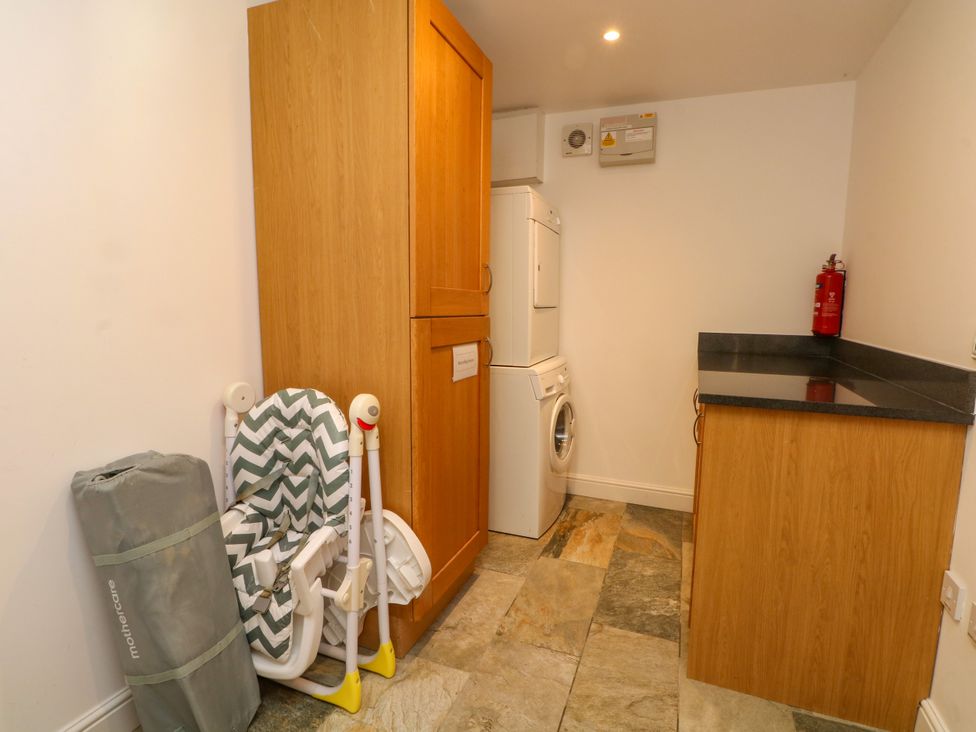 A utility room with a laundry machine and storage cabinet at Plas Tirion Cottage in Mostyn near Holywell