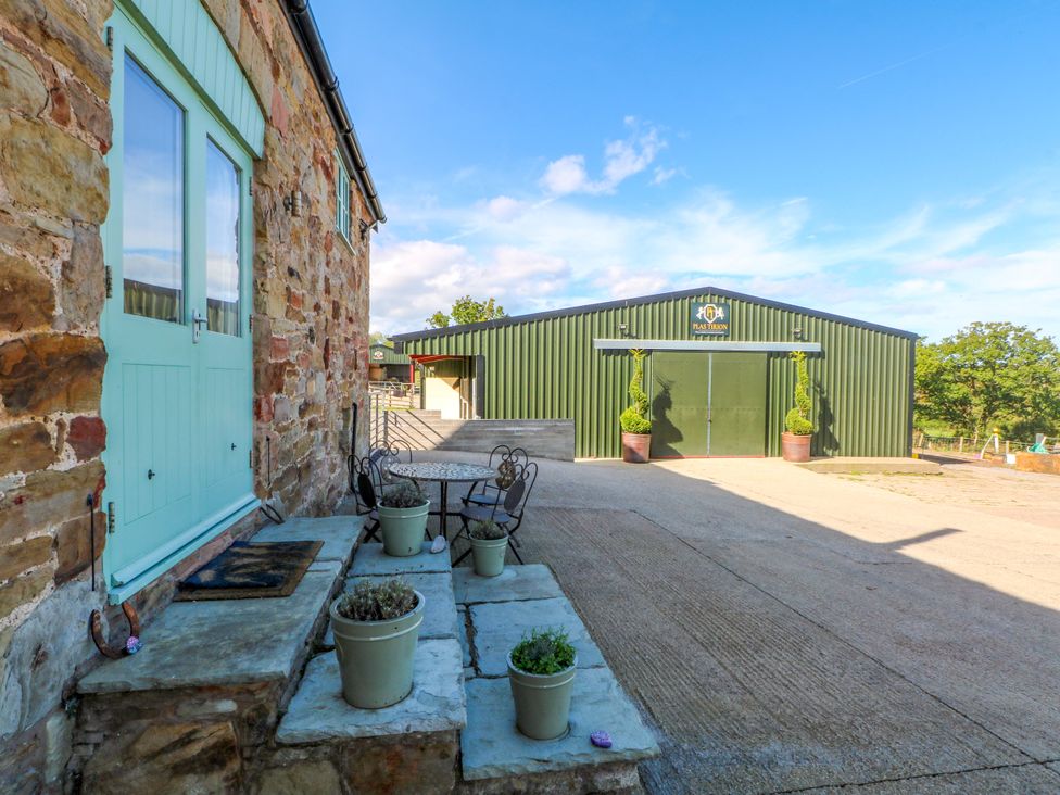 An outdoor area with stone steps and a green building at Plas Tirion Cottage Mostyn near Holywell
