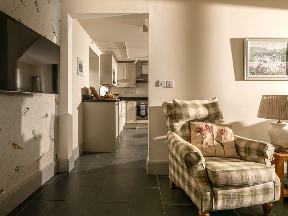 A kitchen with an armchair and television at Shepherds Cottage in Llandrillo