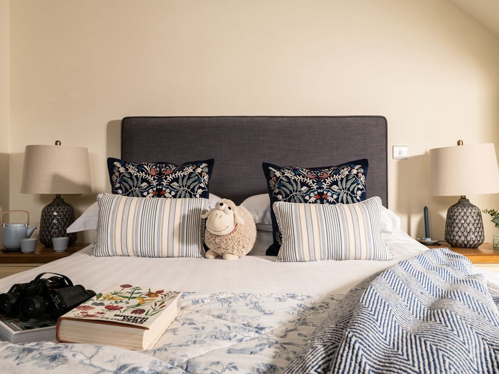 A bedroom with a bed and decorative pillows at Shepherds Cottage in Llandrillo