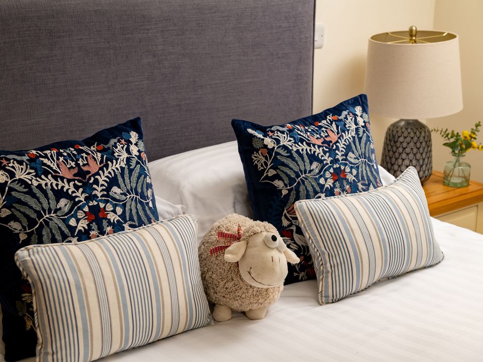A bedroom with pillows and a sheep plush toy at Shepherds Cottage in Llandrillo