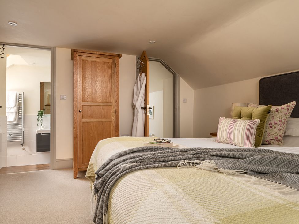 A bedroom with a bed and access to a bathroom at Shepherds Cottage in Llandrillo