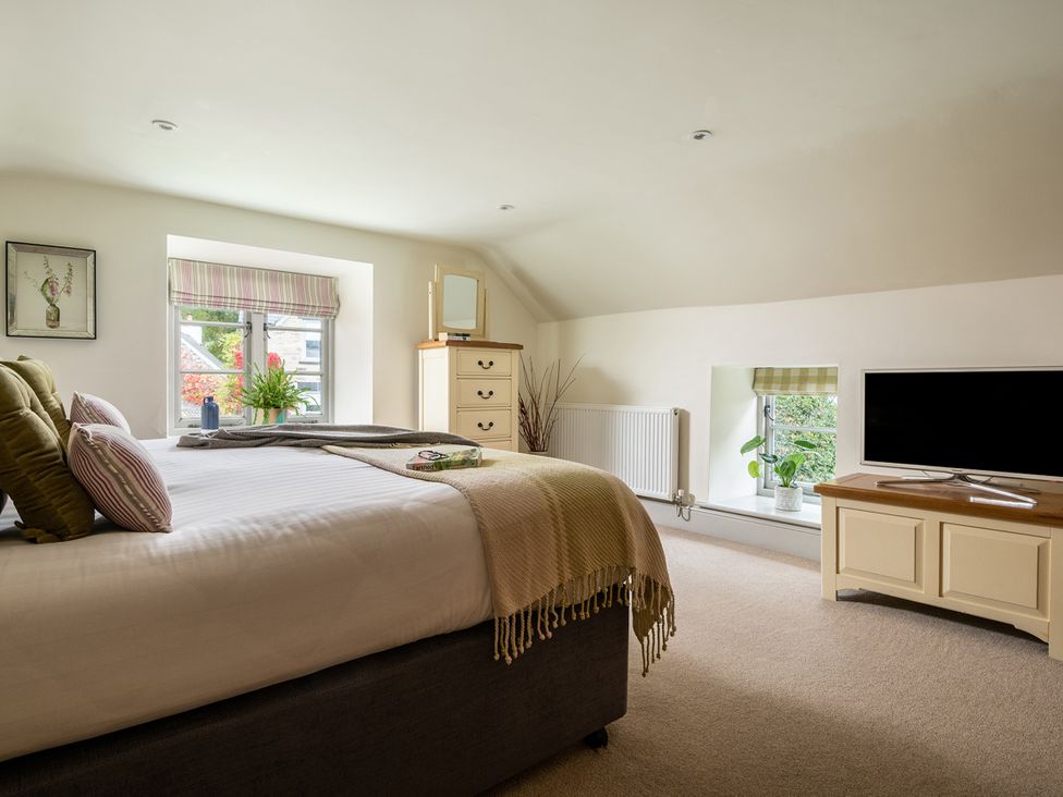 A bedroom with a bed and television at Shepherds Cottage in Llandrillo