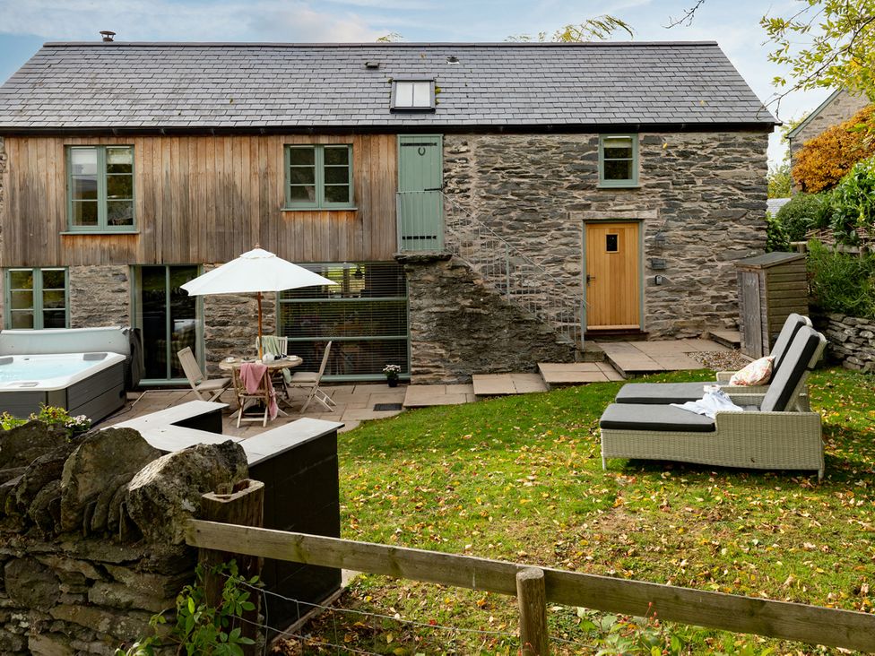 A garden with a hot tub and seating area at Shepherds Cottage in Llandrillo