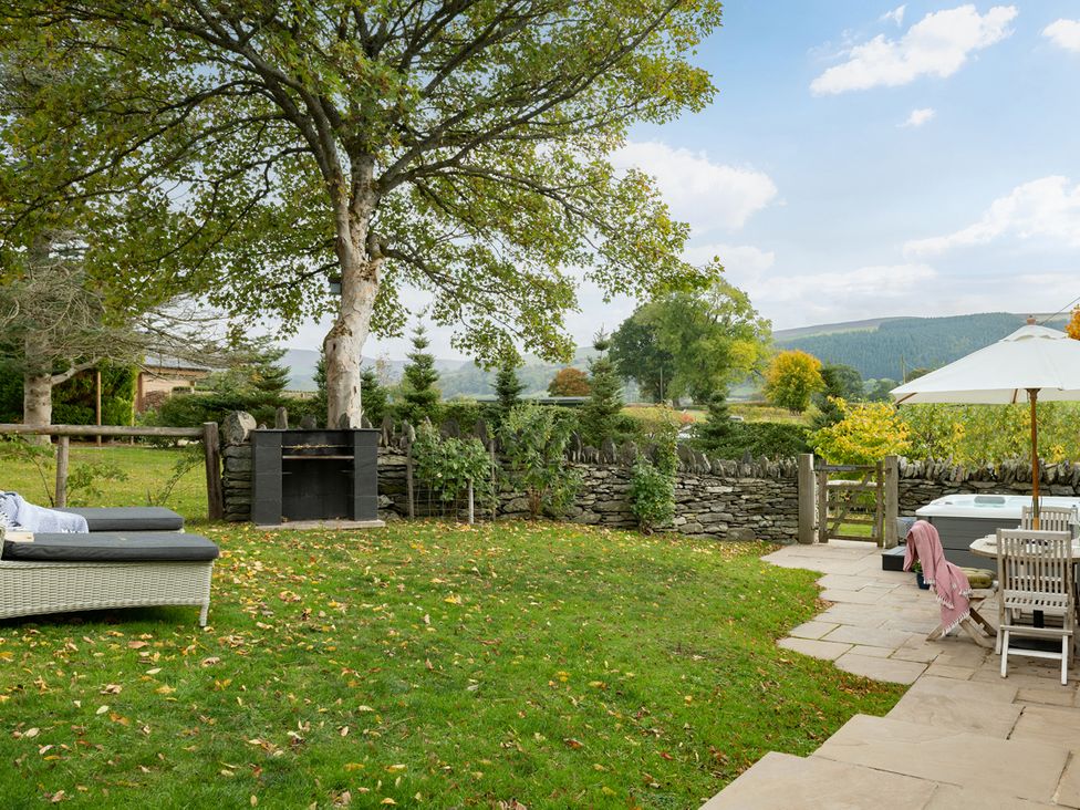 A garden with a sofa and table under an umbrella at Shepherds Cottage in Llandrillo