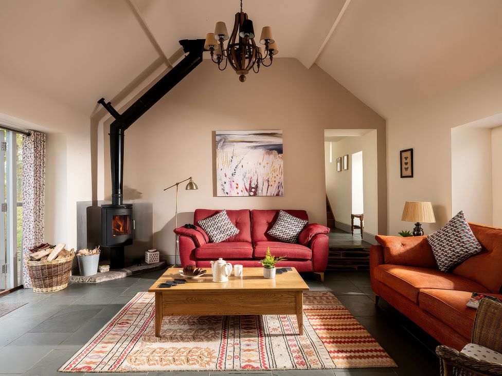 A living room with a wood stove and two sofas at Flyfishers Cottage in Llandrillo