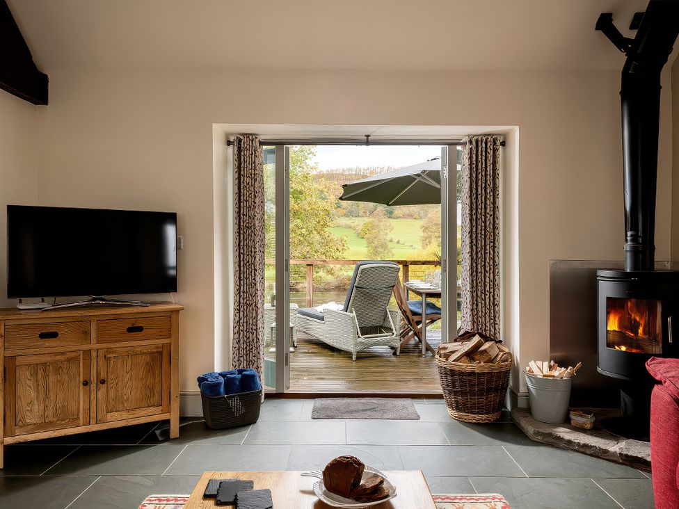 A living room with a television and a fireplace at Flyfishers Cottage in Llandrillo