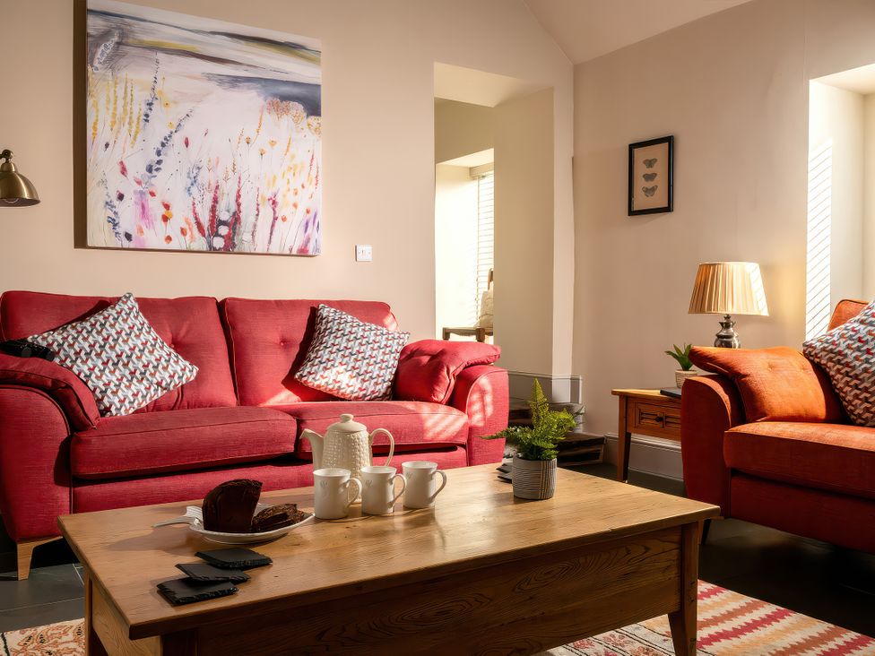 A living room with a sofa, coffee table, and decorations at Flyfishers Cottage in Llandrillo