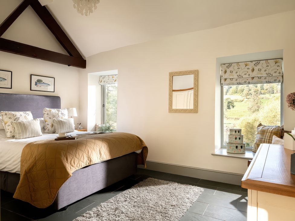 A bedroom with a bed and window view at Flyfishers Cottage Llandrillo
