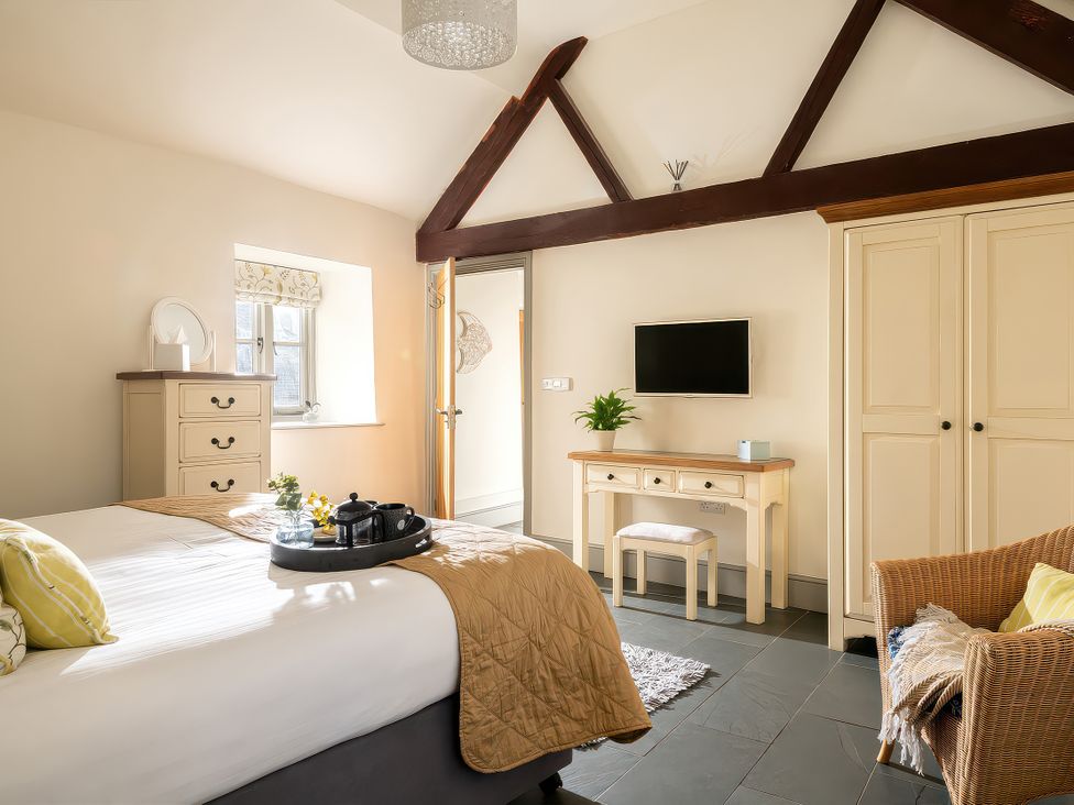 A bedroom with a bed, table, and wardrobe at Flyfishers Cottage in Llandrillo