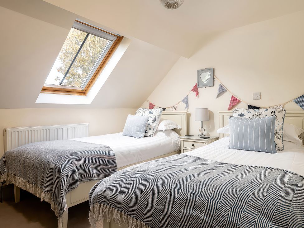 A bedroom with two beds and a window at Flyfishers Cottage in Llandrillo