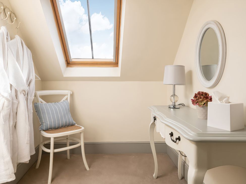 A dressing room with a chair and a lamp at Flyfishers Cottage in Llandrillo