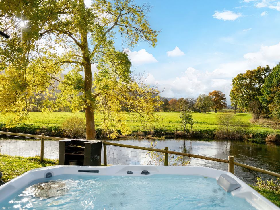 A hot tub with a view of a river and trees at Flyfishers Cottage in Llandrillo