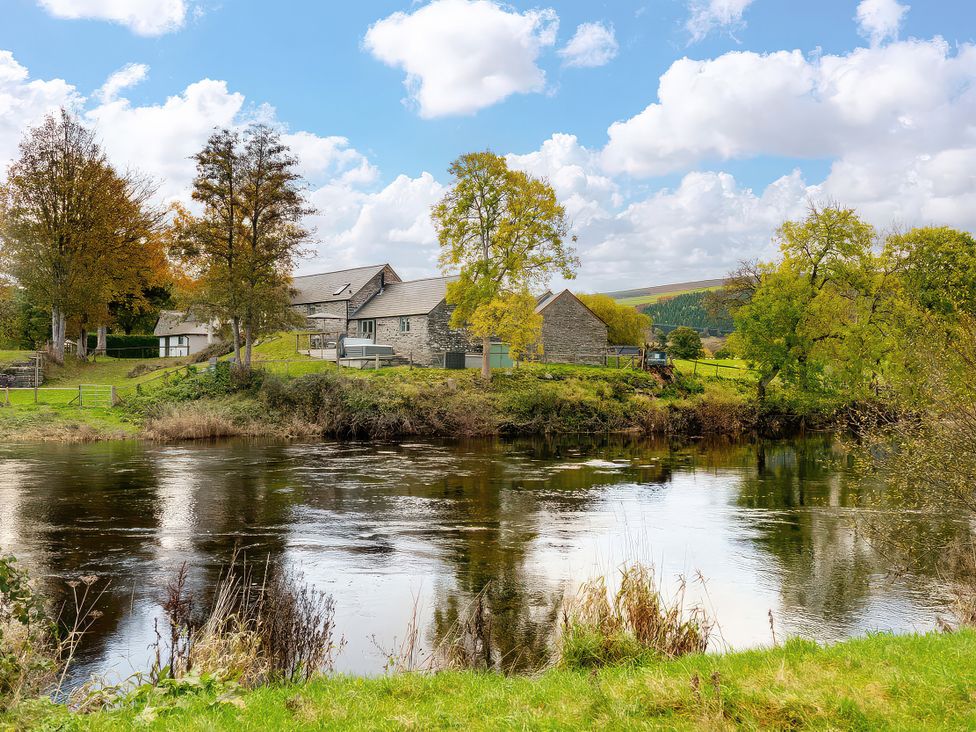 A river with fields and trees at Flyfishers Cottage in Llandrillo