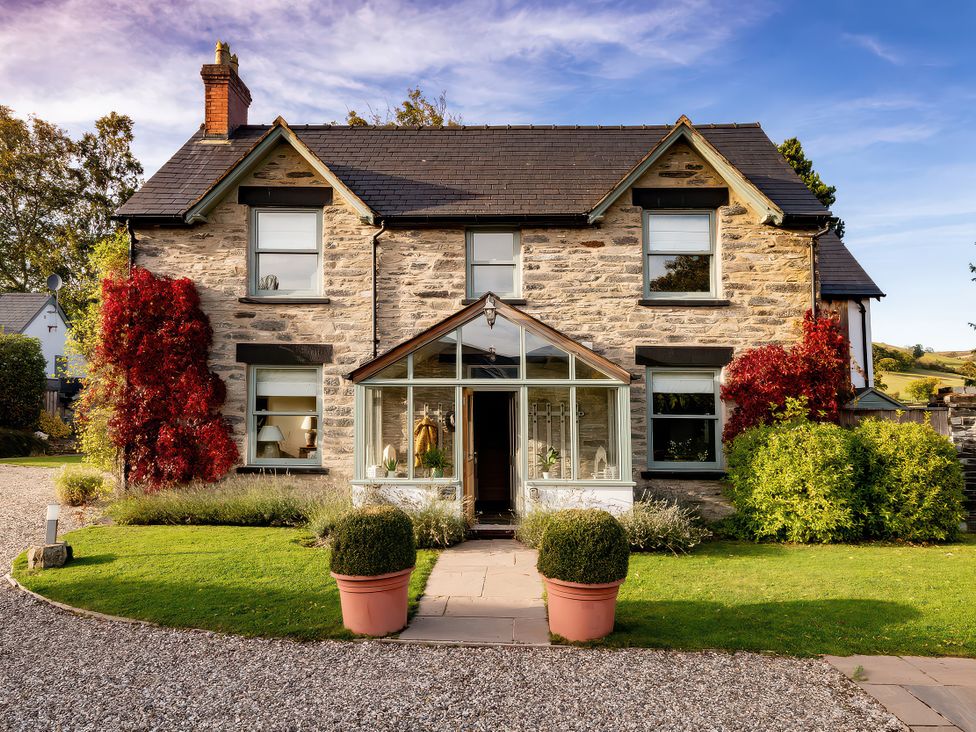 A house with a glass porch and garden at Cilan Farmhouse in Llandrillo