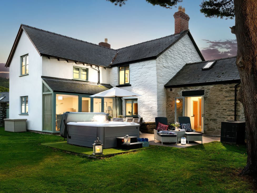 An outdoor area with a hot tub and seating at Cilan Farmhouse in Llandrillo